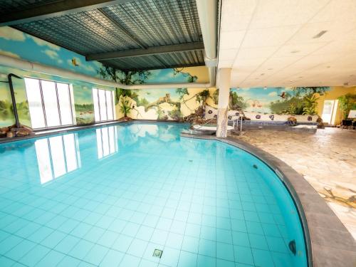 an indoor swimming pool with a mural on the wall at Chalet by the Water in Leukermeer in Well