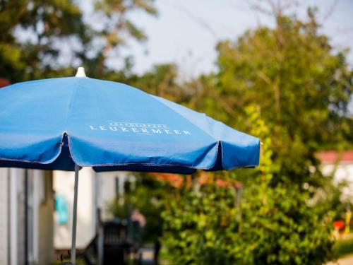 a blue umbrella sitting in front of a house at Chalet by the Water in Leukermeer in Well