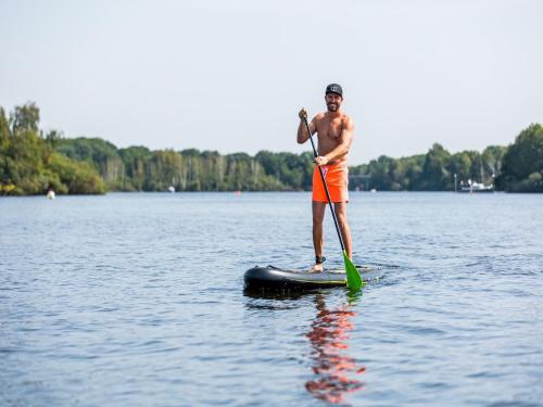 a man standing on a paddle board on a lake at Chalet by the Water in Leukermeer in Well