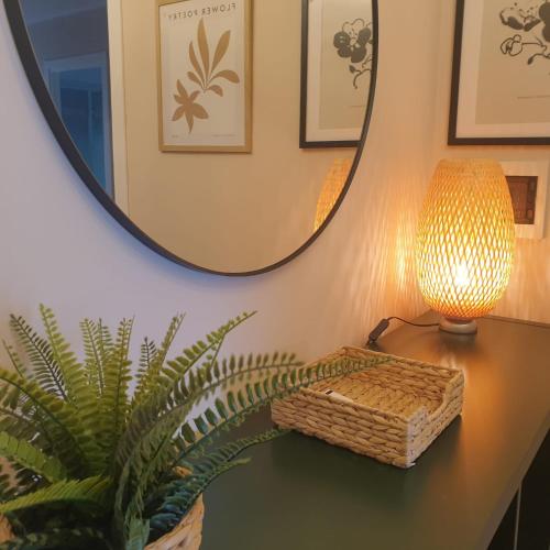 a table with a lamp and a plant and a mirror at Appartamento Centrale Ladispoli in Ladispoli