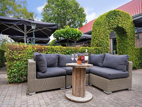 a patio with two couches and a table with wine glasses at Holiday Home in Diessen near Tilburg 