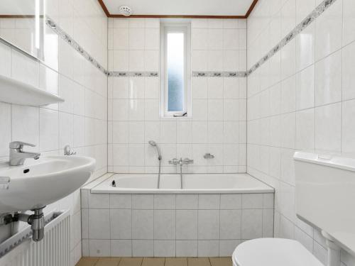 a white bathroom with a tub and a sink at Sauna Retreat by the Lake in Brouwershaven