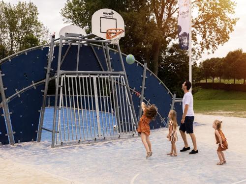 a man and two children playing basketball on a playground at Sauna Retreat by the Lake in Brouwershaven
