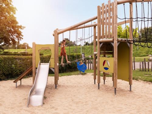 a girl is playing on a slide at a playground at Sauna Retreat by the Lake in Brouwershaven