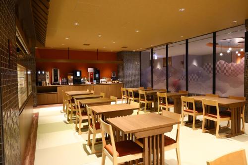 a restaurant with wooden tables and chairs and a counter at Dormy Inn Express Unnan Natural Hot Spring in Satogata