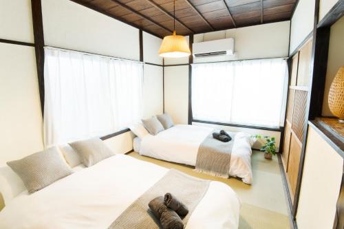 two beds in a room with windows at Close to Shinjuku! 3BR House for 10, Kids Welcome, High-Speed Wi-Fi in Tokyo