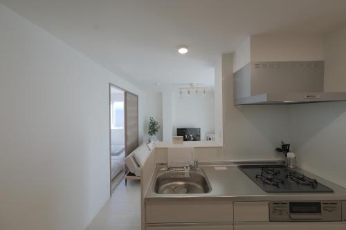 a small kitchen with a sink and a stove at Cozy Nest Nakano 2 stops 5 min to Ikebukuro 7 stops to Shinjuku 15 min new 1LDK in Tokyo