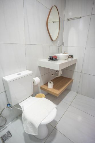 a white bathroom with a toilet and a sink at Pousada Aconchego Noronha in Fernando de Noronha