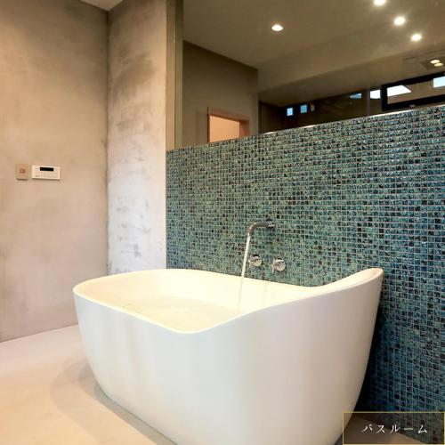 a bath tub in a bathroom with a green tiled wall at Hotel 4CROWNS-PREMIERE シルバープラン in Katsuyama