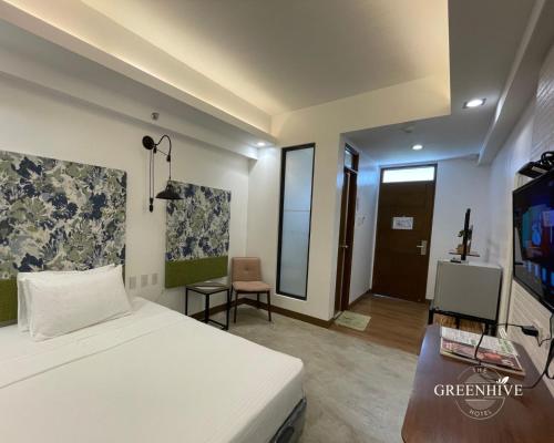 a bedroom with a bed and a tv and a room at The Greenhive Hotel in Ibaan