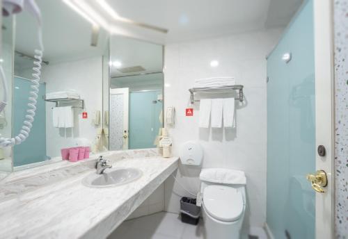 a bathroom with a sink and a toilet and a mirror at Ohotel in Taichung