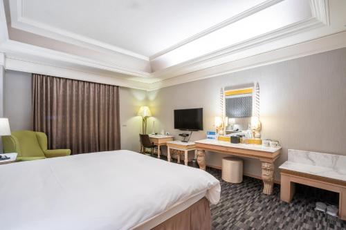a hotel room with a bed and a desk and a television at Ohotel in Taichung