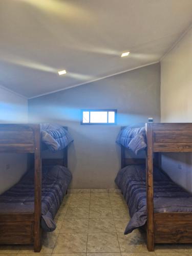 Tres literas en una habitación con ventana. en Hospedaje El Quincho2, en Gobernador Gregores