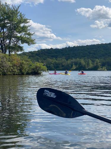 a boat sitting on a lake with people in kayaks at Emerald Escape Lake, Theater, Game Room & More! in Long Pond