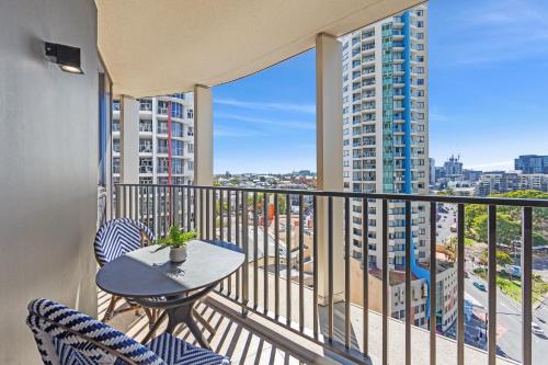 a balcony with a table and chairs and a view of a city at Spire Residences by CLLIX in Brisbane