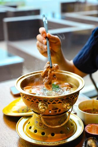 a person is eating food in a bowl of soup at Four Points by Sheraton Urumqi in Ürümqi