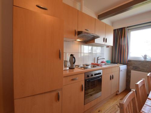 a kitchen with wooden cabinets and a stove at Group house with 3 apartment for family in Amblève