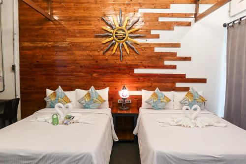 two beds in a room with a wooden wall at AV Suites in Puerto Galera