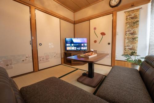 a living room with a couch and a table and a tv at Skytree Tokyo House Takasago in Tokyo