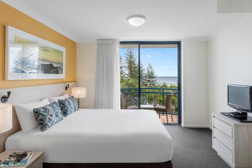 a hotel room with a bed and a balcony at Oaks Gold Coast Calypso Plaza Suites in Gold Coast