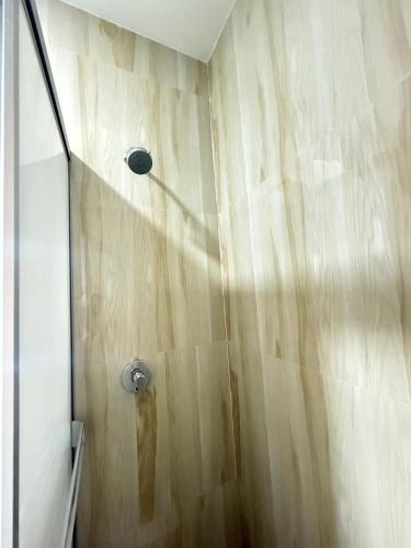 a shower in a bathroom with a wooden wall at Hostal Cieza in Chiclayo