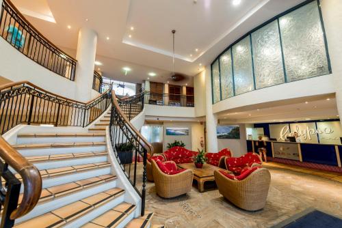 a living room with a staircase and red chairs at Oaks Gold Coast Calypso Plaza Suites in Gold Coast