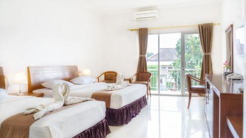 a hotel room with three beds and a balcony at HOTEL & WISMA BINTANG JADAYAT in Bogor