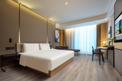 a bedroom with a large white bed and a desk at Atour Hotel Suzhou Wuzhong Taihu New Town in Suzhou