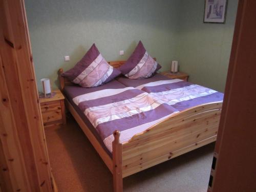 a bedroom with a wooden bed with purple sheets and pillows at Gästehaus Jüngling in Kottenborn