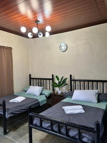 two beds in a room with a clock on the wall at Kabbalay Homestay in San Juan