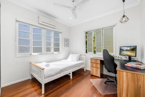 a bedroom with a bed and a desk with a computer at Spacious Queenslander Retreat in Belgian Gardens
