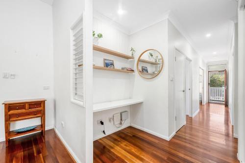 a living room with white walls and wooden floors and a mirror at Spacious Queenslander Retreat in Belgian Gardens