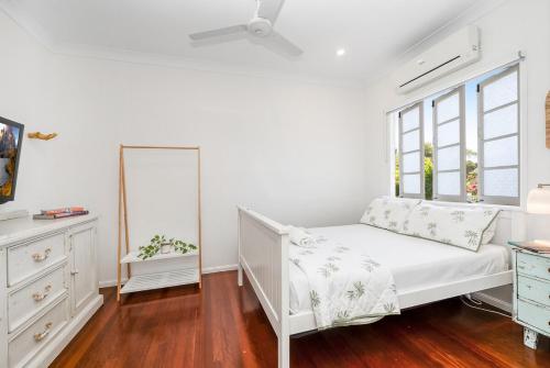 a white bedroom with a bed and a window at Spacious Queenslander Retreat in Belgian Gardens