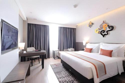 a hotel room with a large bed and a television at Patra Cirebon Hotel & Convention in Cirebon