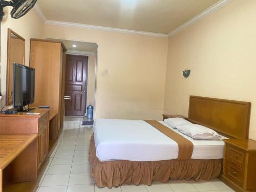 a hotel room with a bed and a flat screen tv at HOTEL & WISMA BINTANG JADAYAT in Bogor