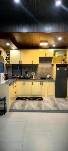 a kitchen with yellow cabinets and a black refrigerator at E2Paz Staycation and Guesthouse in Bayombong