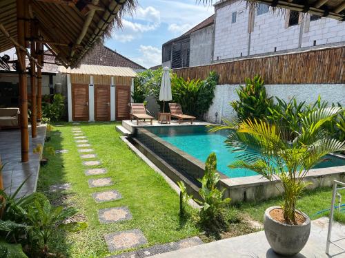 a swimming pool in a yard with chairs and a house at NOMAD Tropical Hotel Canggu in Dalung