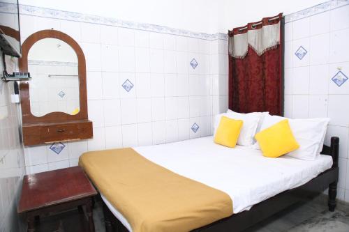 a bedroom with a bed with yellow pillows and a mirror at Zam zam residents in Chennai