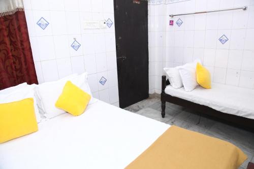 a room with two beds with yellow pillows and a couch at Zam zam residents in Chennai