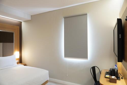 a bedroom with a bed and a tv on a wall at Front One Hotel Papua Lestari in Timika