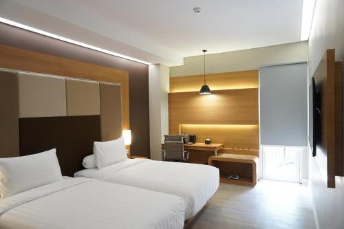 a hotel room with two beds and a desk at Front One Hotel Papua Lestari in Timika