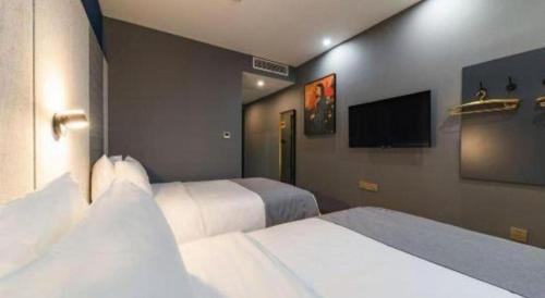 a hotel room with two beds and a flat screen tv at LANO Hotel Shandong Qingdao Jimo District Baolong Square in Qingdao