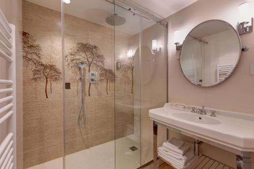 La salle de bains est pourvue d'une douche, d'un lavabo et d'un miroir. dans l'établissement Hotel Muguet, à Paris