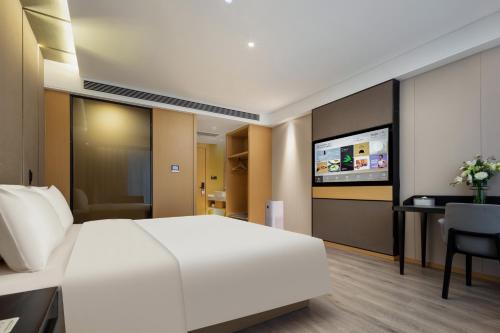 a bedroom with a white bed and a desk and a tv at Atour Hotel Suzhou Wuzhong Taihu New Town in Suzhou