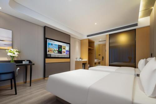 a hotel room with two beds and a desk and a tv at Atour Hotel Suzhou Wuzhong Taihu New Town in Suzhou