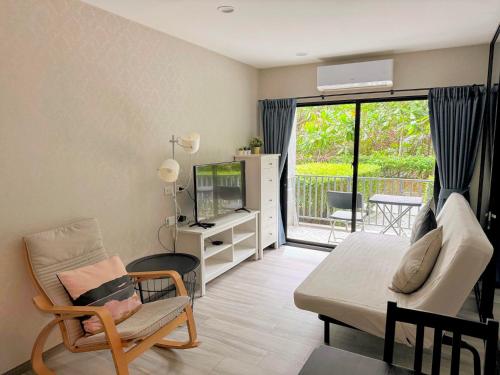 a living room with a tv and a couch and a chair at The Title Residencies Naiyang by Beringela in Nai Yang Beach