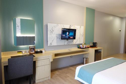 a bedroom with a desk with a tv and a bed at Grand Kangen Hotel Urip Sumoharjo in Yogyakarta