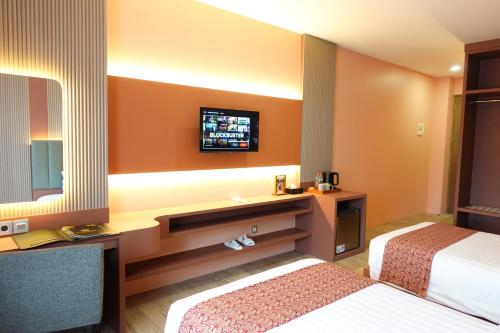 a hotel room with two beds and a tv at Grand Kangen Hotel Urip Sumoharjo in Yogyakarta
