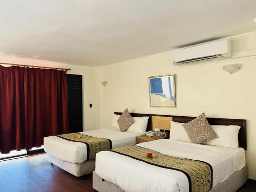 two beds in a hotel room with red curtains at Mana Island Resort & Spa - Fiji in Mana Island
