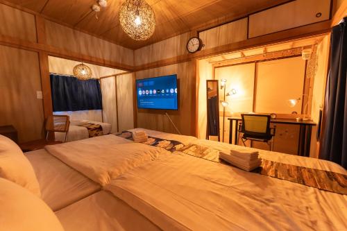 a bedroom with a large bed and a tv at Skytree Tokyo House Takasago in Tokyo